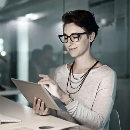 woman reviewing tablet in front of computer
