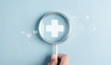 A human hand holding magnifying glass hovering over general health insurance agency logo