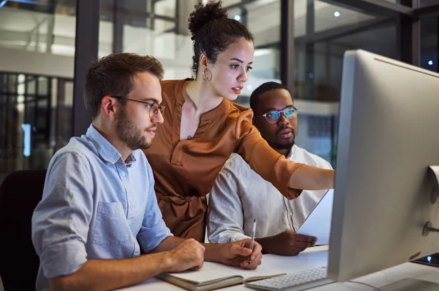 Colleagues, two men and one woman working together reviewing information Colleagues, two men and one woman working together reviewing information